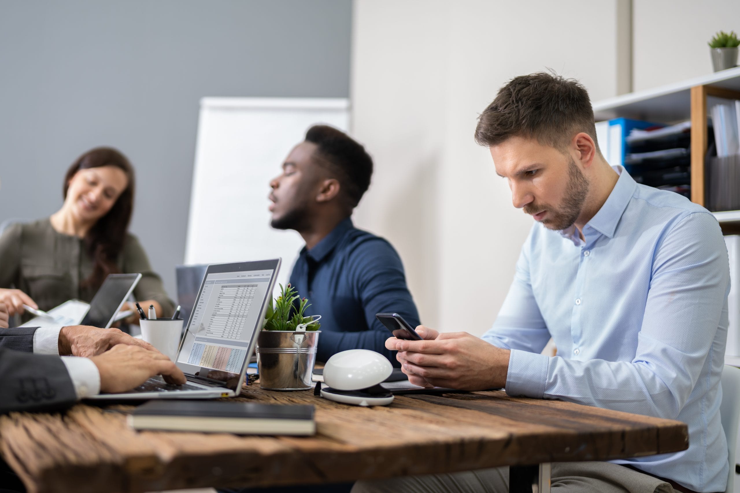 Man looking at phone in team meeting